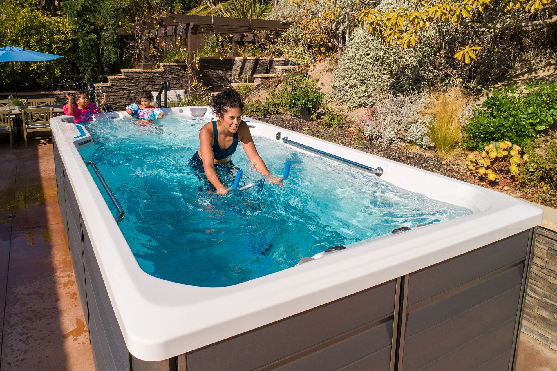 Family enjoying an Endless Pools SwimCross swim spa in a backyard