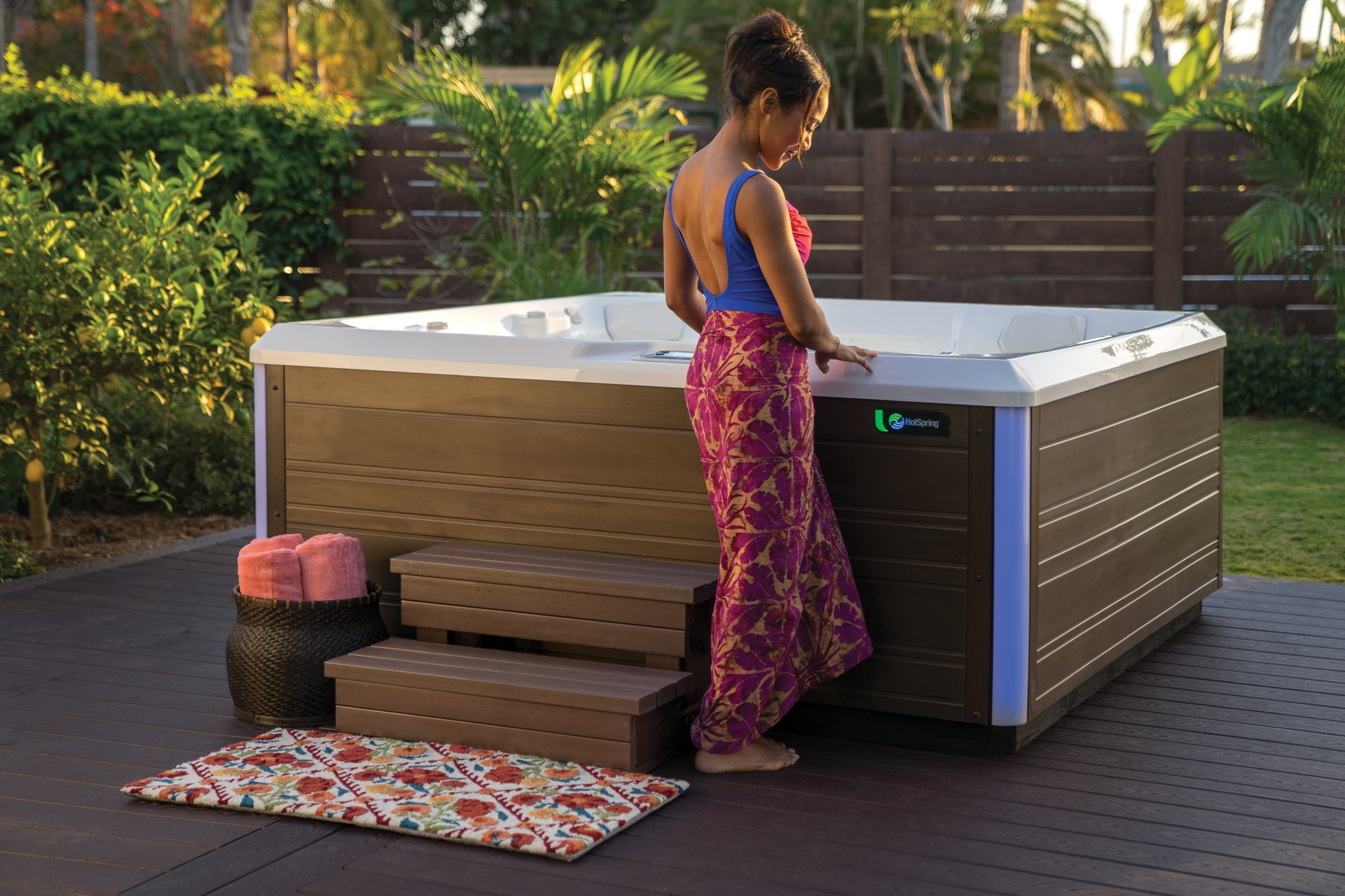 Woman stepping up to a Hot Spring Limelight Flair hot tub on a backyard deck