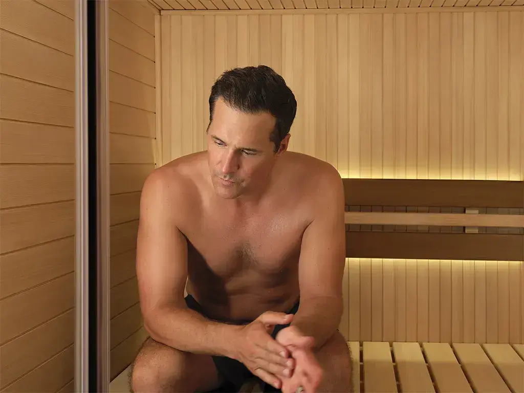 Man relaxing on the bench of a traditional Tylo sauna